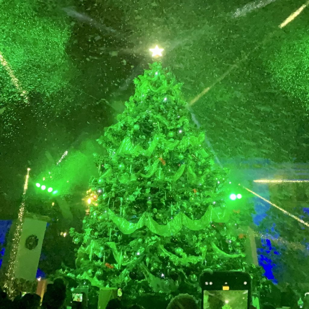 Glistening Christmas tree, covered in LED lights, lit up all green, with falling snow, at the Paramount Studios lot in Hollywood, CA. Music for the event was created by EmotionCrafters.